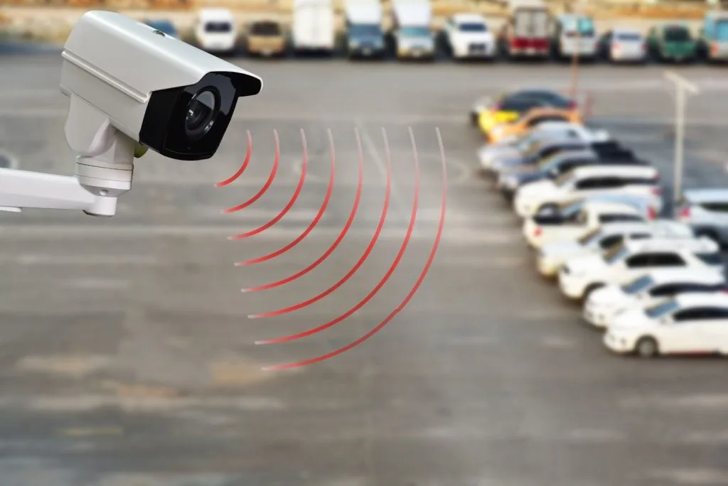 A security camera watching over rows of parked cars